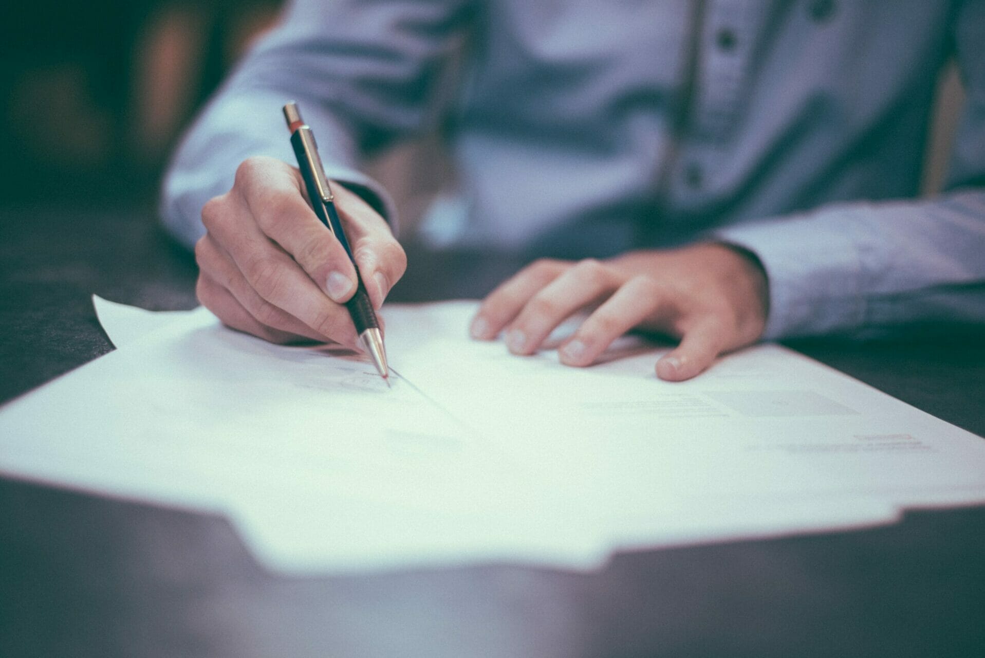 man writing on notepaper at a desk